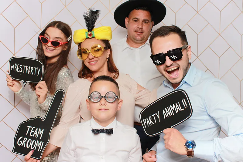 Familie cu pancarte haioase „Team Groom” și „Best Party” la cabina foto